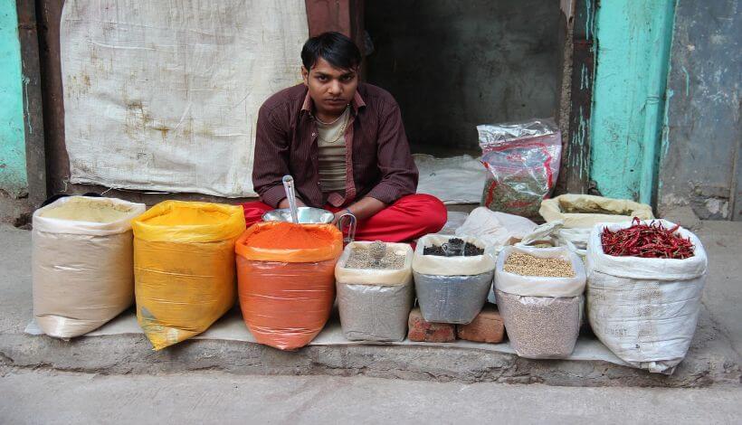 Ein Händler sitzt auf einer Straße von Delhi, mit einigen Säcken von verschiedenen Gewürzen, um Sie zu verkaufen.