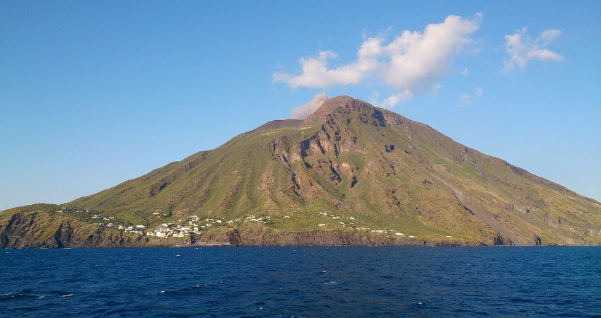 Ein kleines Dorf mit einem Vulkan im Hintergrund.