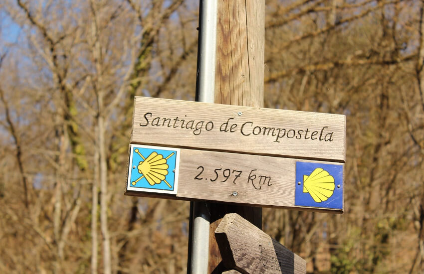 Ein Wegweiser nach Santiago de Compostela, wo die noch zu bewältigen 2597 Kilometer angegeben sind.