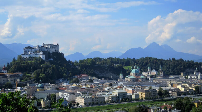 Die Stadt Salzburg von der Ferne fotografiert, wobei die Festung Hohensalzburg im Hintergrund zu sehen ist.