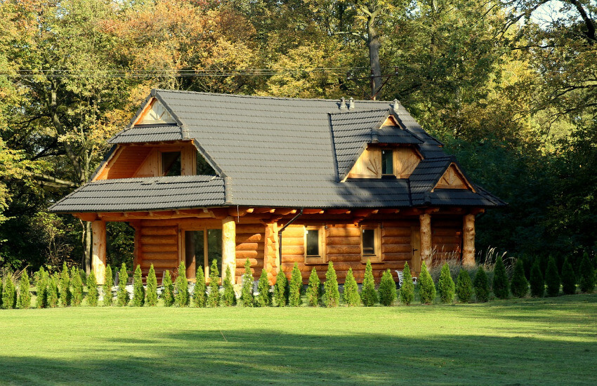 Ein relativ neues Blockferienhaus mit einem frisch gemähten Rasen davor.