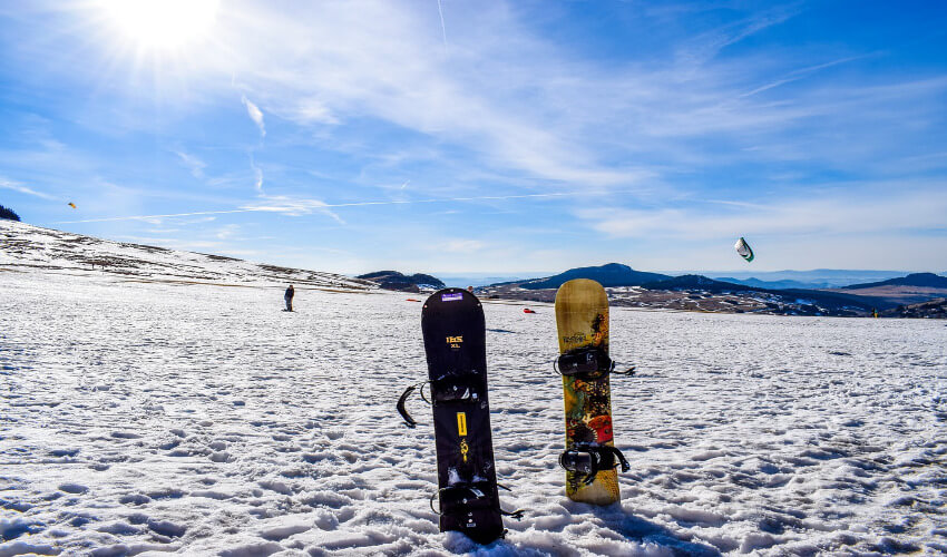 Zwei Snowboards stecken im Schnee.