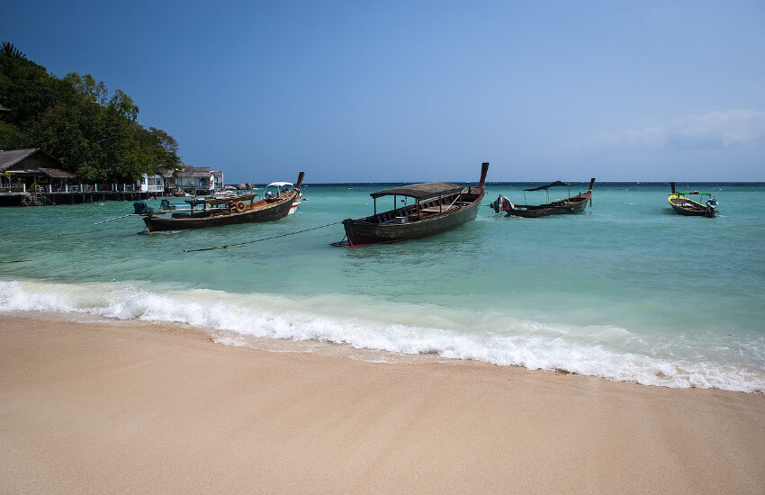 Strand, wo vier Holzboote für Touristen Ausflüge ankern.