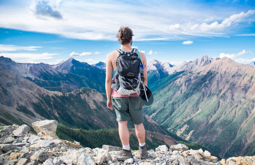 Ein Mann steht hoch oben am Berg und genießt die Aussicht.