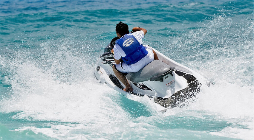 Ein Mann mit einem weißen Jetski unterwegs im blauen Meer.