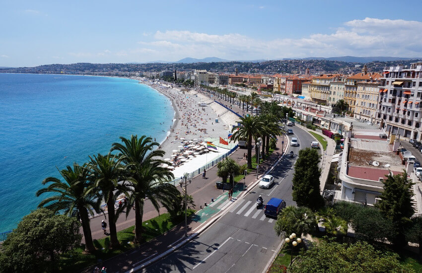 Ein lang gezogener Strand mit der Stadt Nizza direkt dahinter.