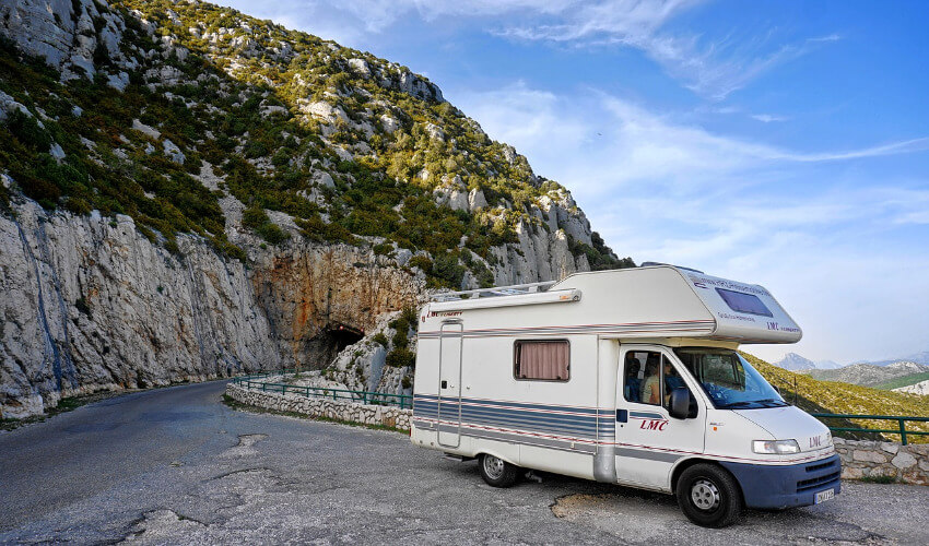 Ein Wohnmobil parkt am Rand einer kurvigen Bergstraße.