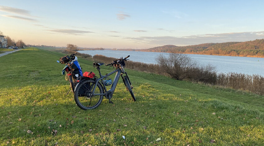 Zwei E-Bikes parken auf der Wiese und im Vordergrund die Elbe.