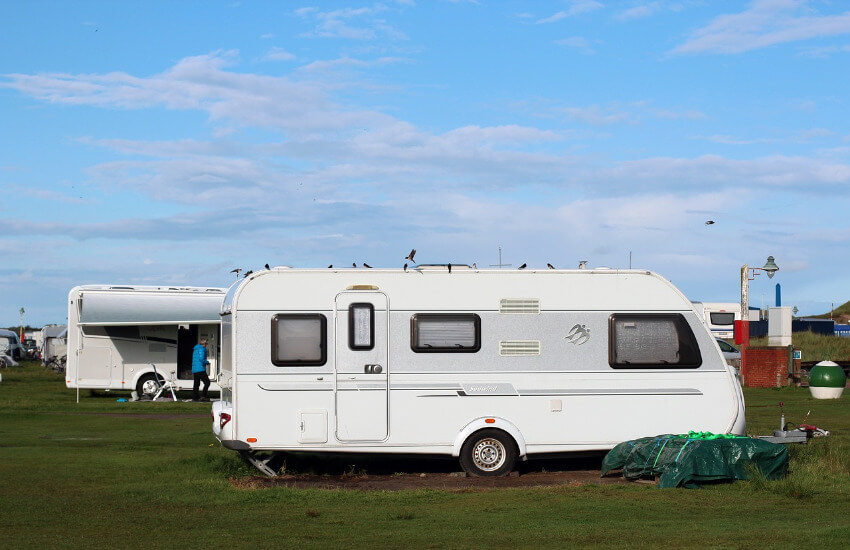 Besetzte Stellplätze für Wohnmobile auf einer Wiese auf einem Campingplatz.