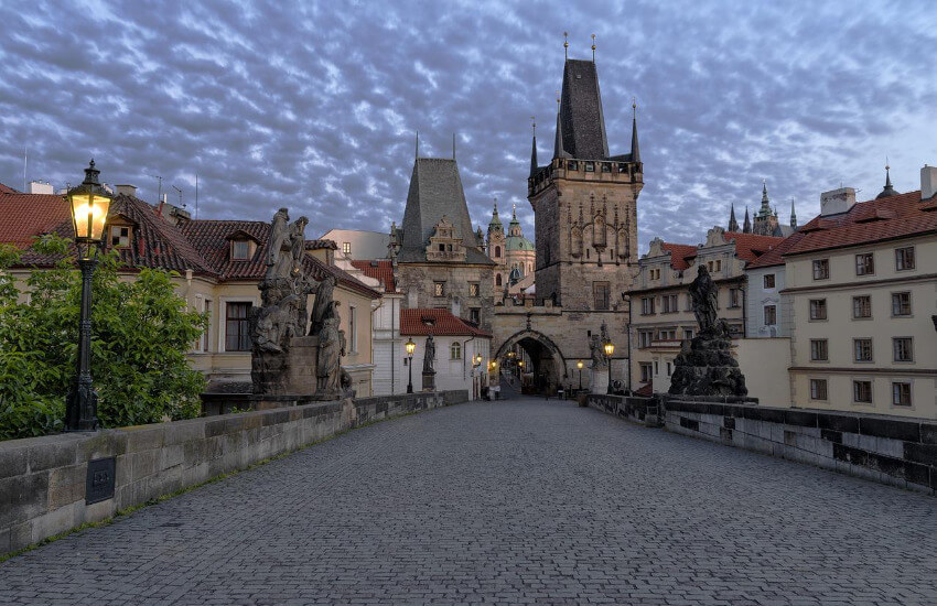 Die mit Steinen gepflasterte Karlsbrücke und im Hintergrund die Altstadt von Prag.