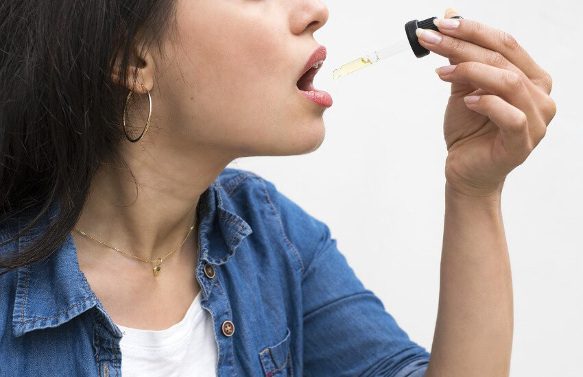 Eine Frau tropft sich CBD Öl in den Mund.