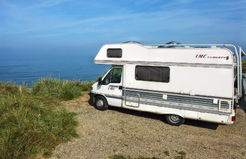 Ein Wohnmobil steht an einer Klippe mit Blickrichtung Meer.