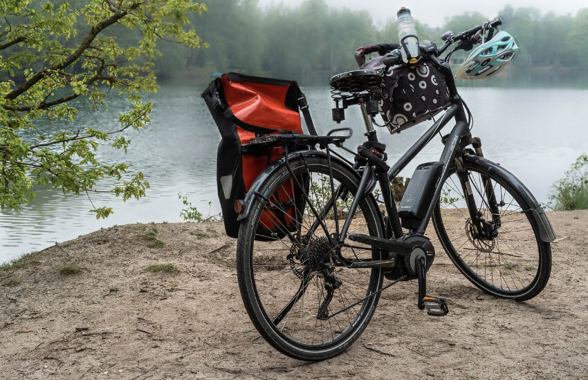 Ein schwarzes E-Bike parkt neben einem Fluss.