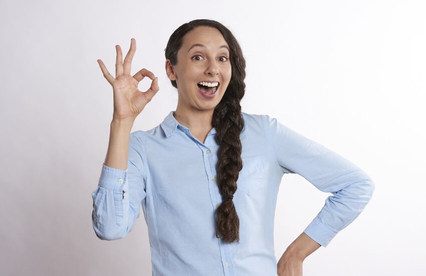 Eine Frau macht ein okay Zeichen. Einen runden Kreise mit Daumen und Zeigefinger.