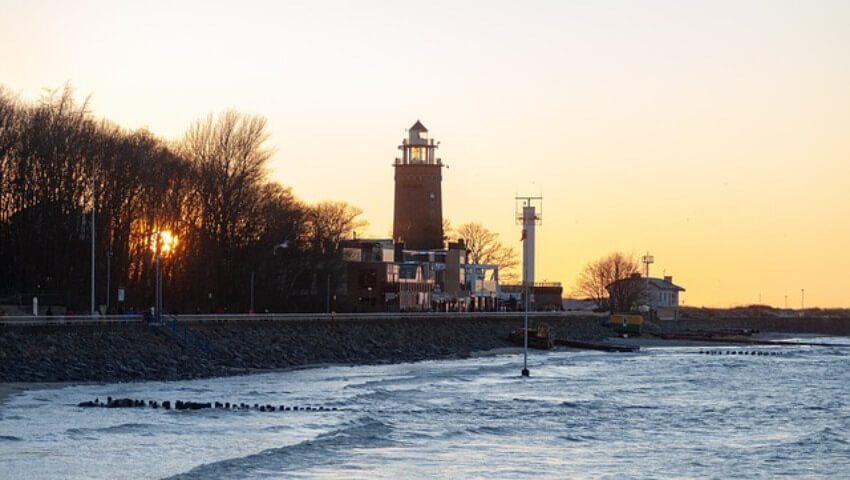 Ein Leuchtturm am Meer beim Sonnenaufgang.