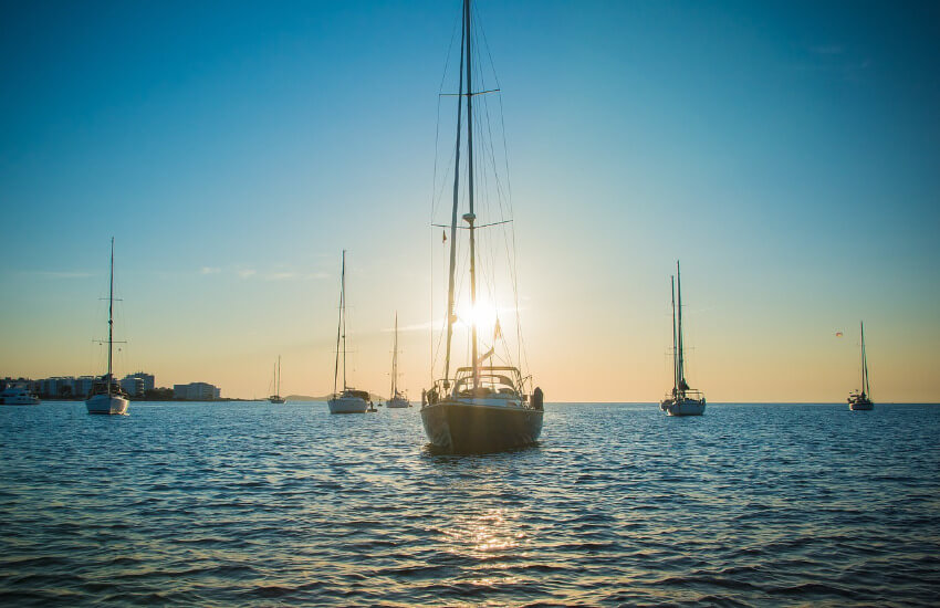 Einige Segelyachten ankern im Meer während des Sonnenuntergangs.