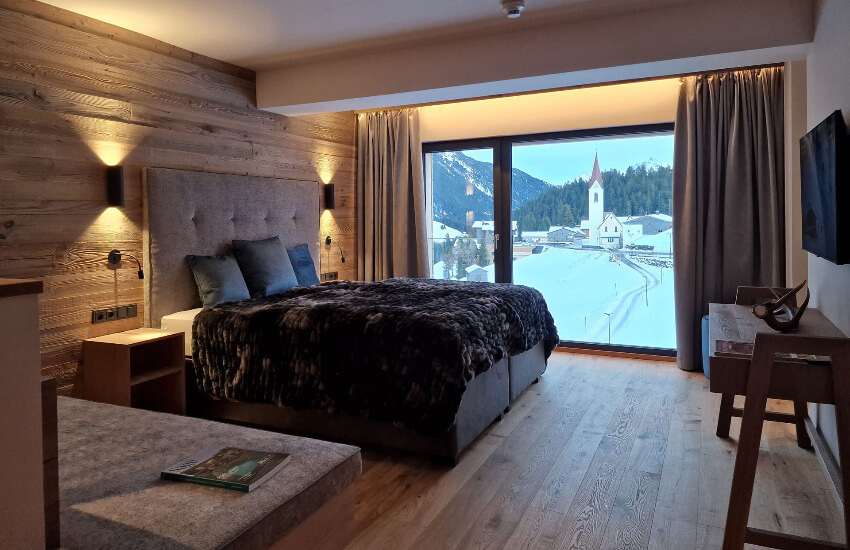 Ein Hotelzimmer mit Altholzwänden und einem Boxspringbett.