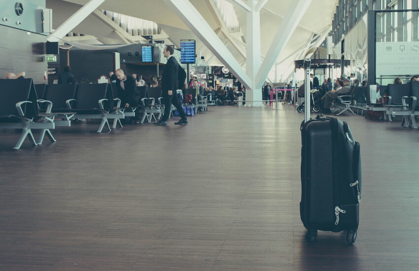 Ein Koffer steht alleine im Wartebereich eines Flughafens.