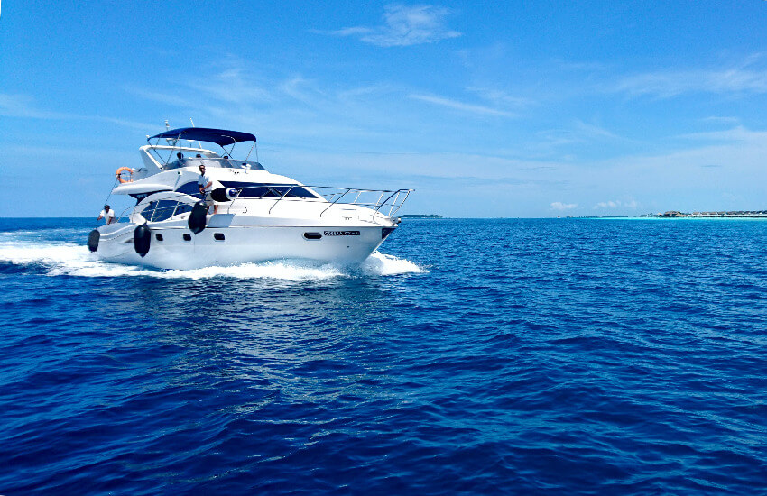 Eine kleine weiße Yacht unterwegs auf dem Meer unter blauem Himmel.
