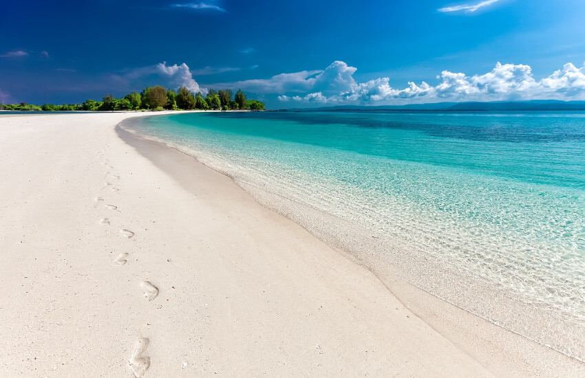 Langer weißer Sandstrand und türkises Meer.