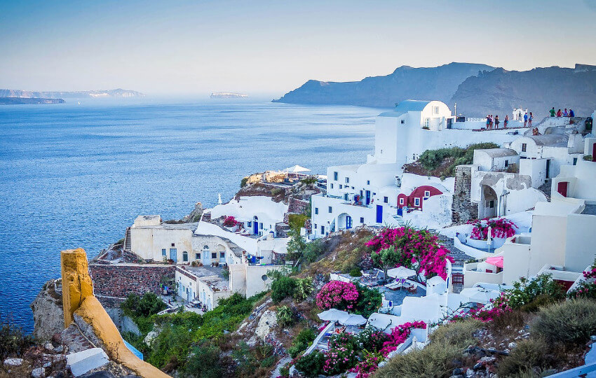 Ein Hügel mit typisch griechischen weißen Häusern und im Hintergrund das Meer.