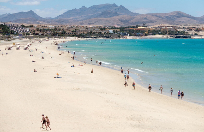 Fuerteventura Strand Strand auf Fuerteventura mit hellem Sand und blauem Meer unter sommerlichem Himmel.