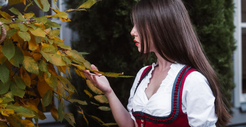 Frau in Tracht Profil einer Frau in Tracht, die in Graz herbstliche Blätter betrachtet.