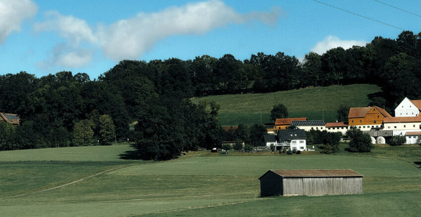 Hügellandschaft mit Bauernhof Ländlicher Blick über Felder und Hofgebäude in Bad Berneck, Deutschland.